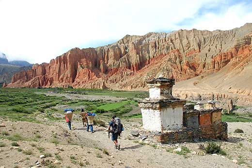 Randonneur et porteurs sur le chemin d’un trekking, au Mustang (Népal). Crédit : Huwans